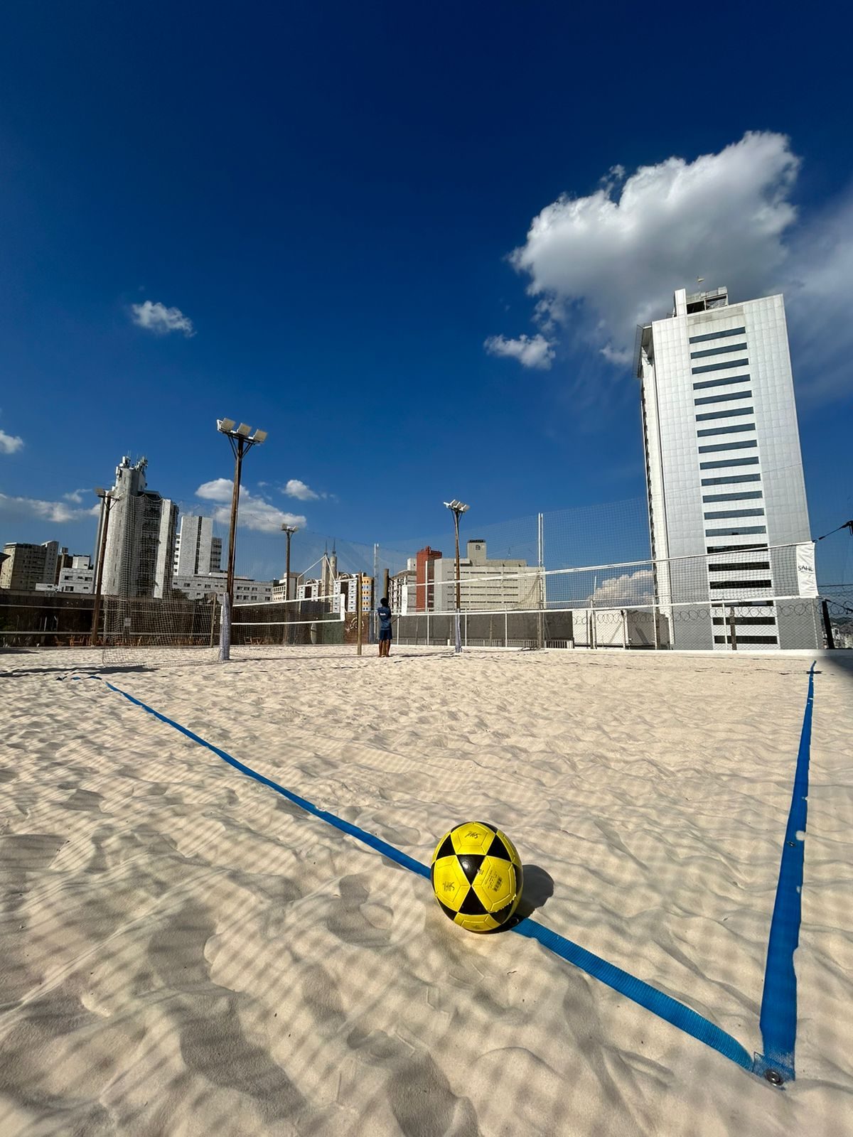 Quadra Sahl com bola na areia e cityscape ao fundo